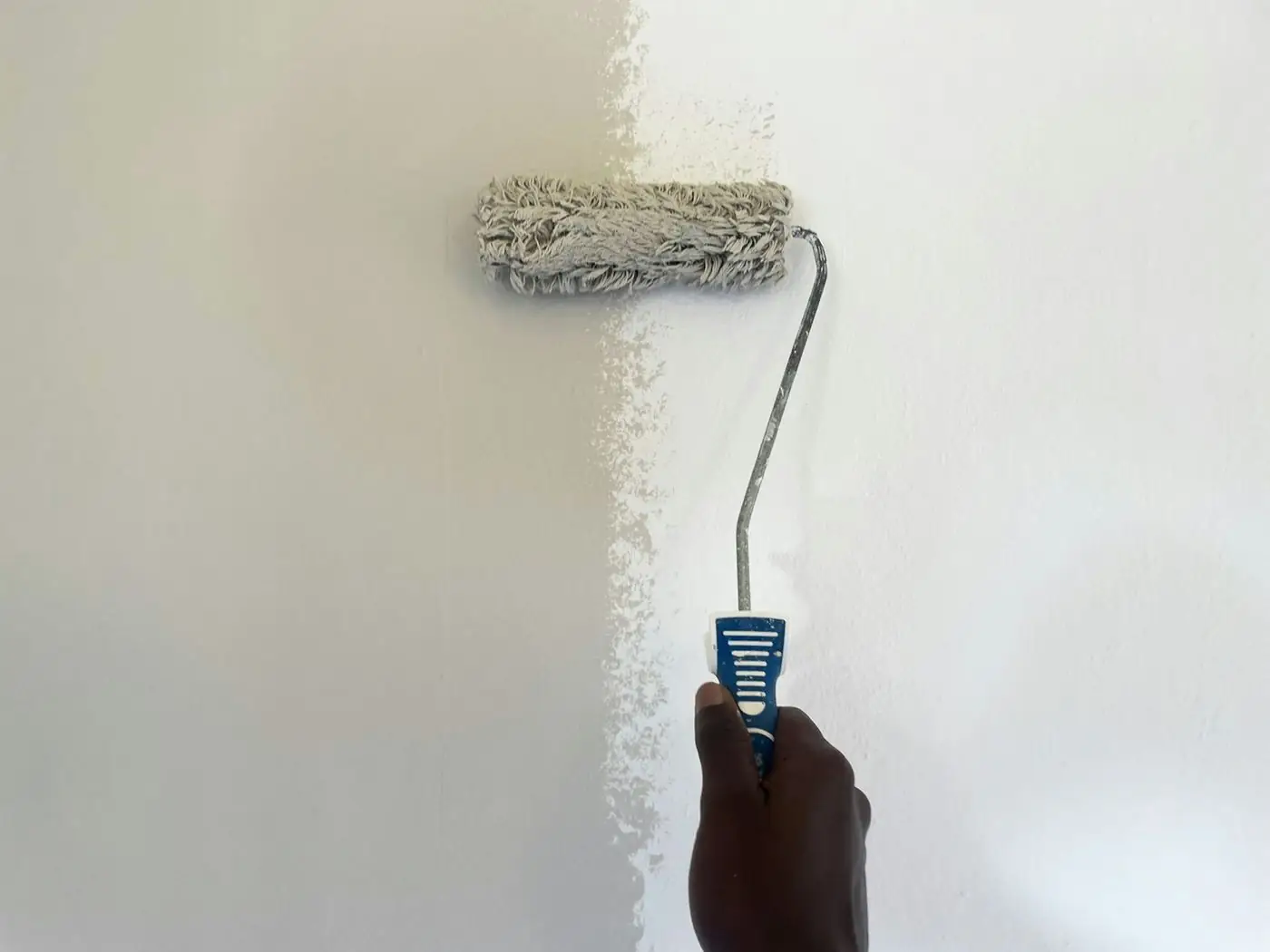 White paint being rolled onto a wall